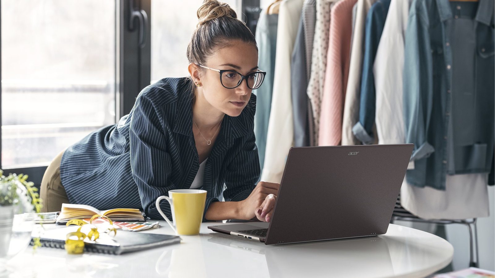 A woman using an Acer Vero 16 laptop at a white table