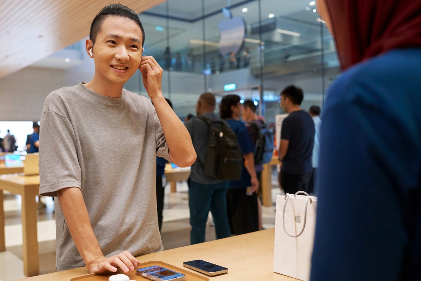 A customer tries AirPods 5 at an Apple Store table