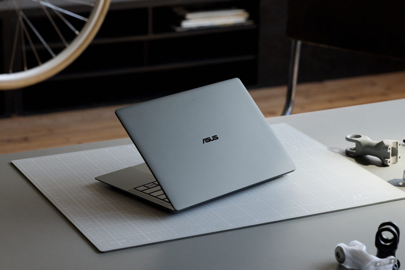 Closed gray ASUS laptop on a cutting mat in a studio