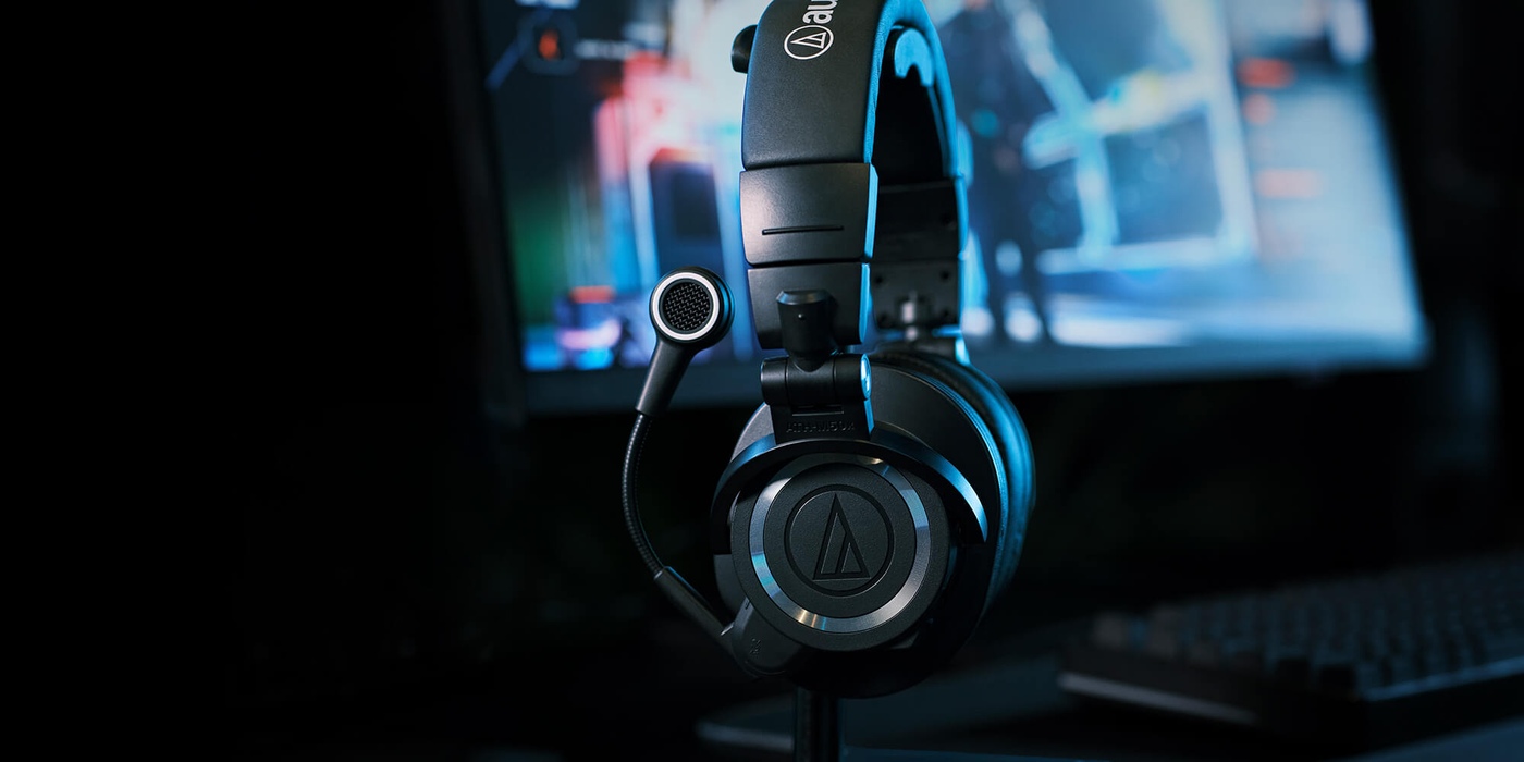The ATH-M50xSTS-WL on a desk stand in front of a gaming setup.