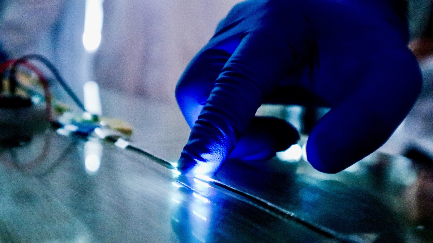 Each fiber carries a layer that senses touch beneath its LEDs, so pressing the thread lights the pixel nearest the finger.