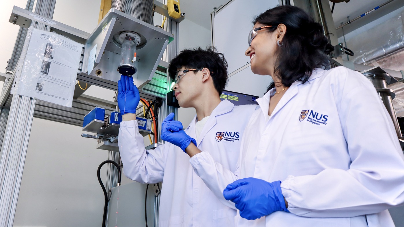 NUS researchers at the thermal drawing tower that pulls the LED strips into one-millimeter fibers.