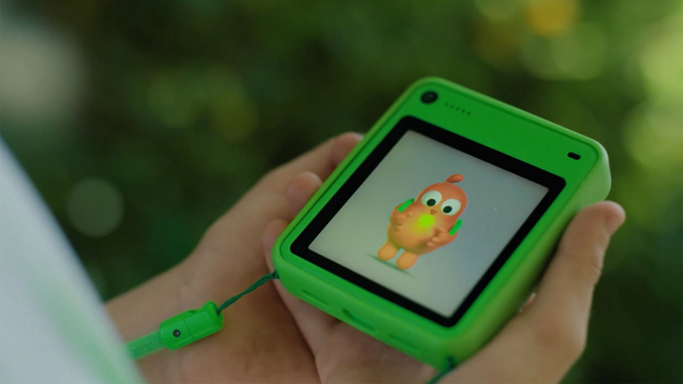 Hands holding green Freckle showing on-screen companion character