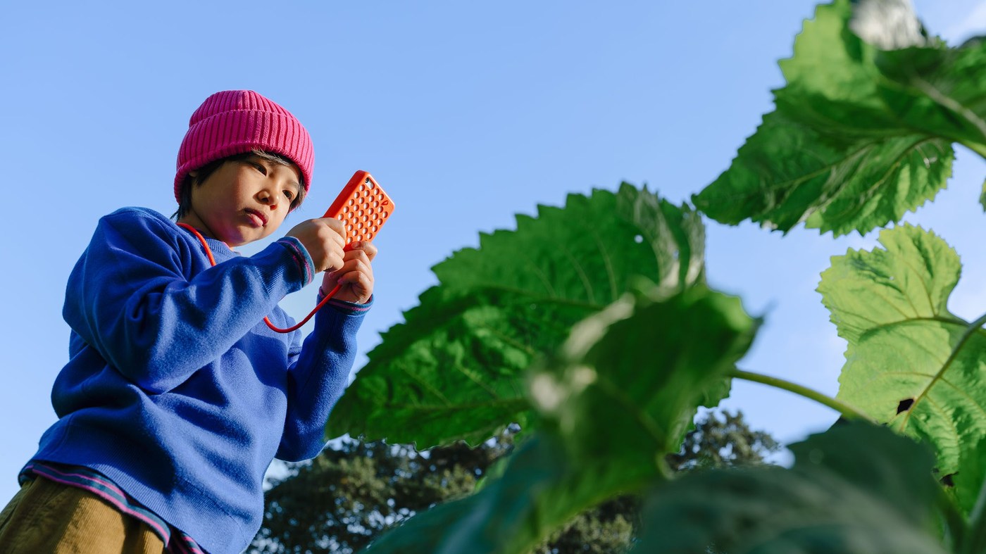 Child in garden holding orange Freckle handset