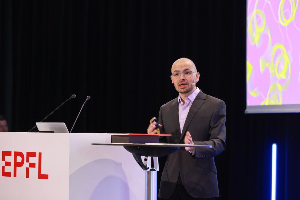 DeepMind chief Demis Hassabis speaking at a podium