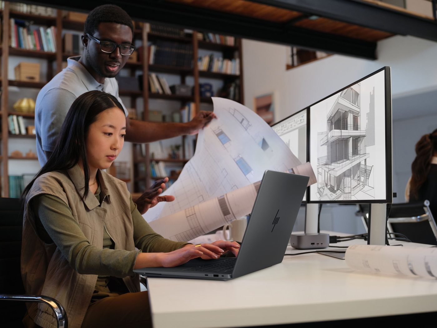 Two architects work at a desk with an HP ZBook Ultra G3a and dual monitors showing a building model
