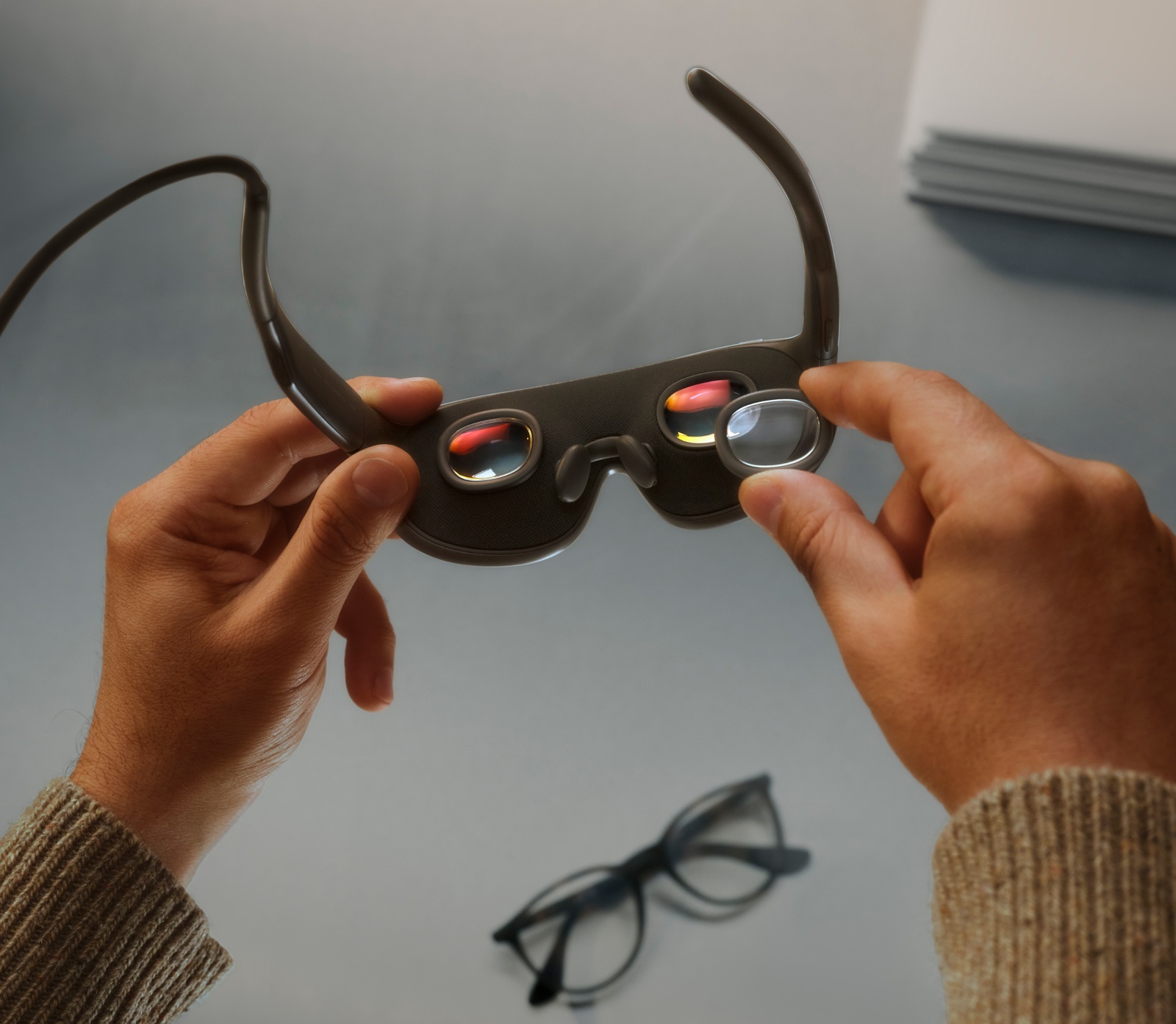 Hands seating a clear lens into the inner frame of Meta VR Glasses