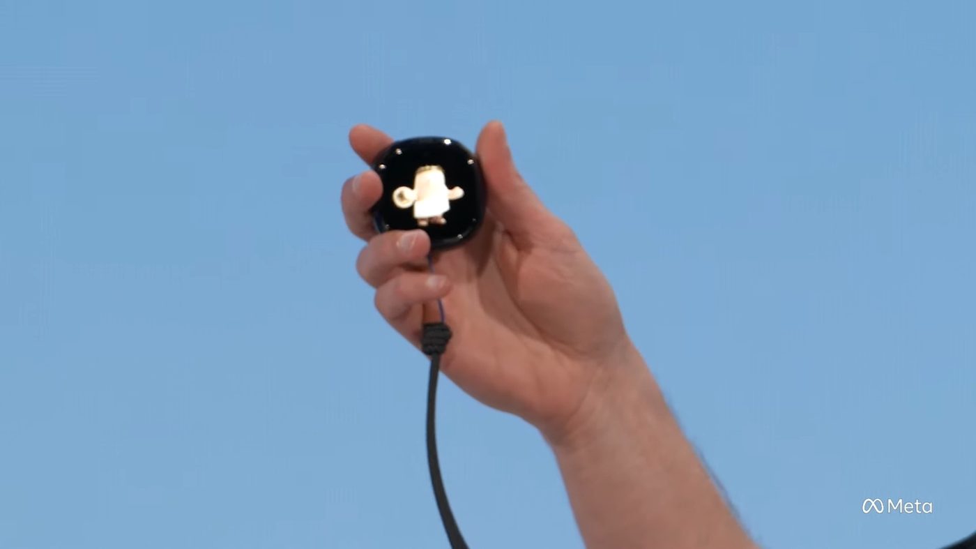 A hand holding Muse Charm against a blue backdrop during the Meta Connect keynote