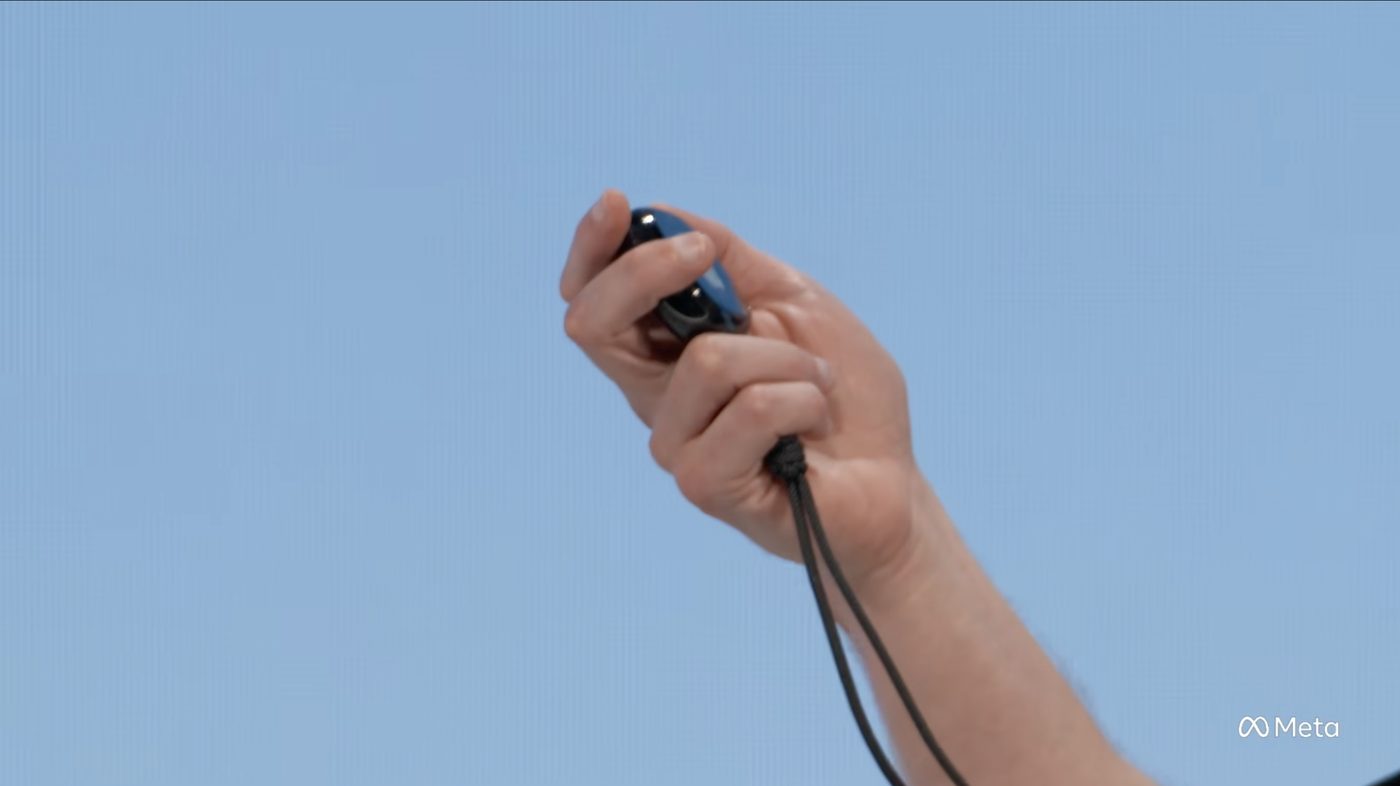 A hand gripping Muse Charm from the side, lanyard hanging down