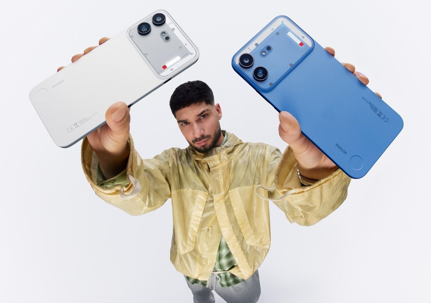 A model holds white and blue Nothing Phone (4b) handsets overhead