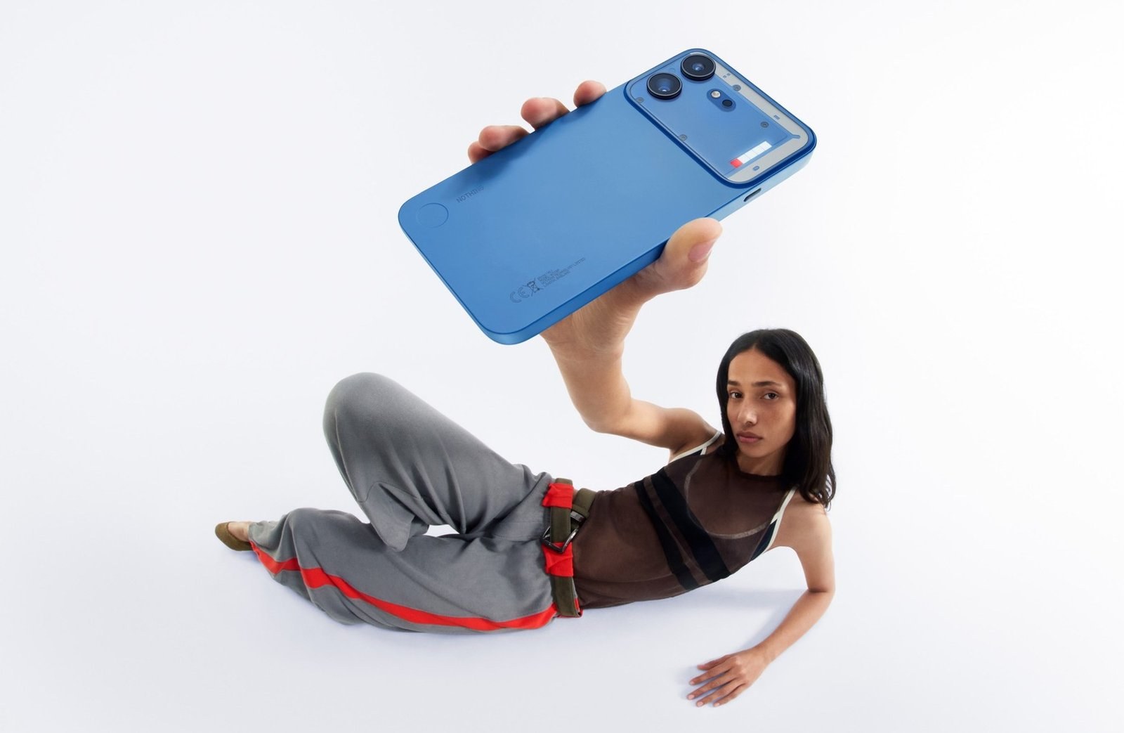A model holds a blue Nothing Phone (4b) above her head
