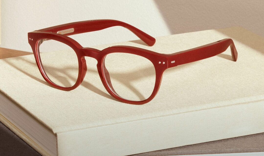 Shiny burgundy Nuance Audio Plus frames resting on a book