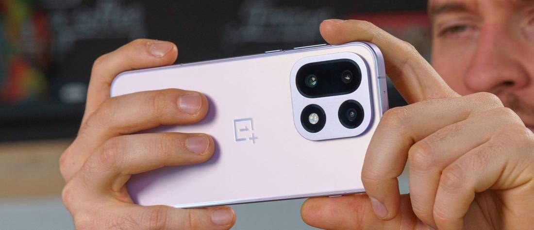 A reviewer holding a purple OnePlus phone in landscape