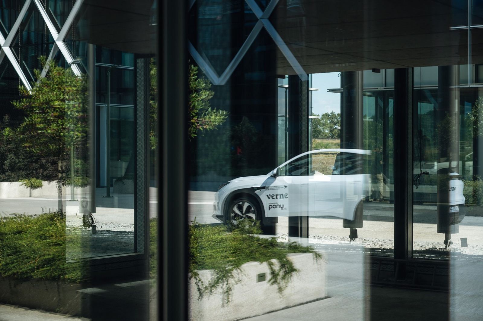 A Verne Pony.ai robotaxi seen through glass at a Zagreb building