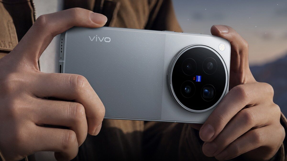 Hands holding a silver Vivo X500 Pro Max, showing the circular ZEISS camera island