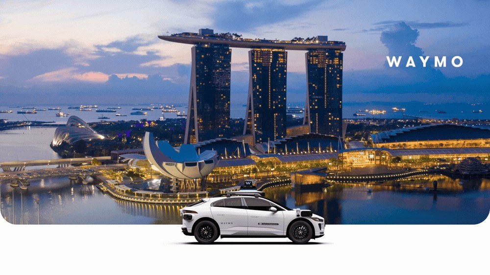 A Waymo Jaguar I-PACE robotaxi on a waterfront with the Singapore skyline