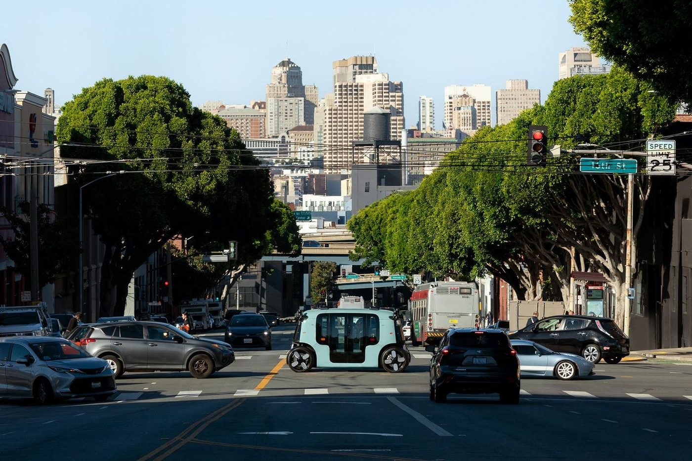 A Zoox robotaxi crossing a San Francisco street under a 16th Street sign